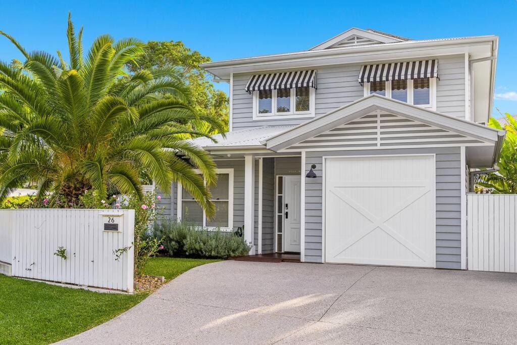 uma casa branca com uma garagem e uma palmeira em Villa Wallah Luxury in Byron Bay em Byron Bay