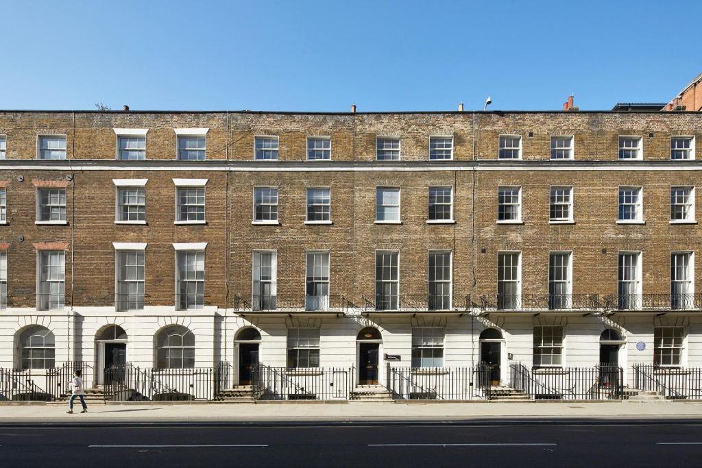 een groot bakstenen gebouw aan de kant van een straat bij Gower Street Houses, Fitzrovia, London in Londen