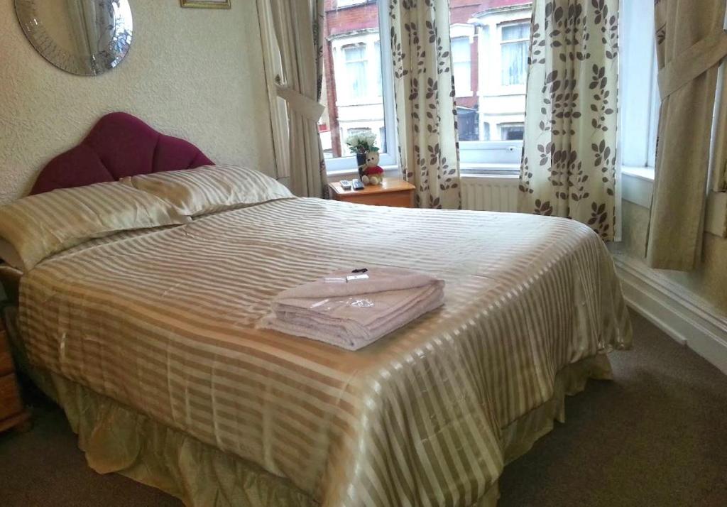 a bedroom with a bed with a pink bag on it at Lynwood Hotel & Spa in Blackpool