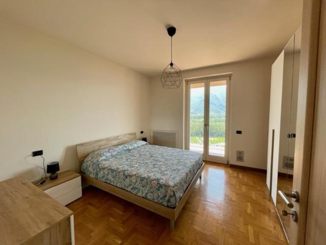 a bedroom with a bed and a large window at Casa CAPONETTI in Costa Volpino