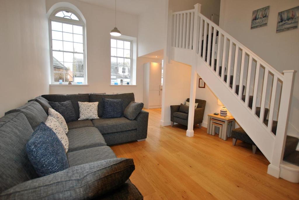 a living room with a couch and a staircase at Walters Neuk Anstruther- luxury coastal home in Anstruther