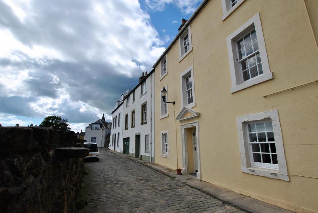 a cobblestone street with yellow and white buildings at Watersedge Apartment- cosy home by the sea in Anstruther