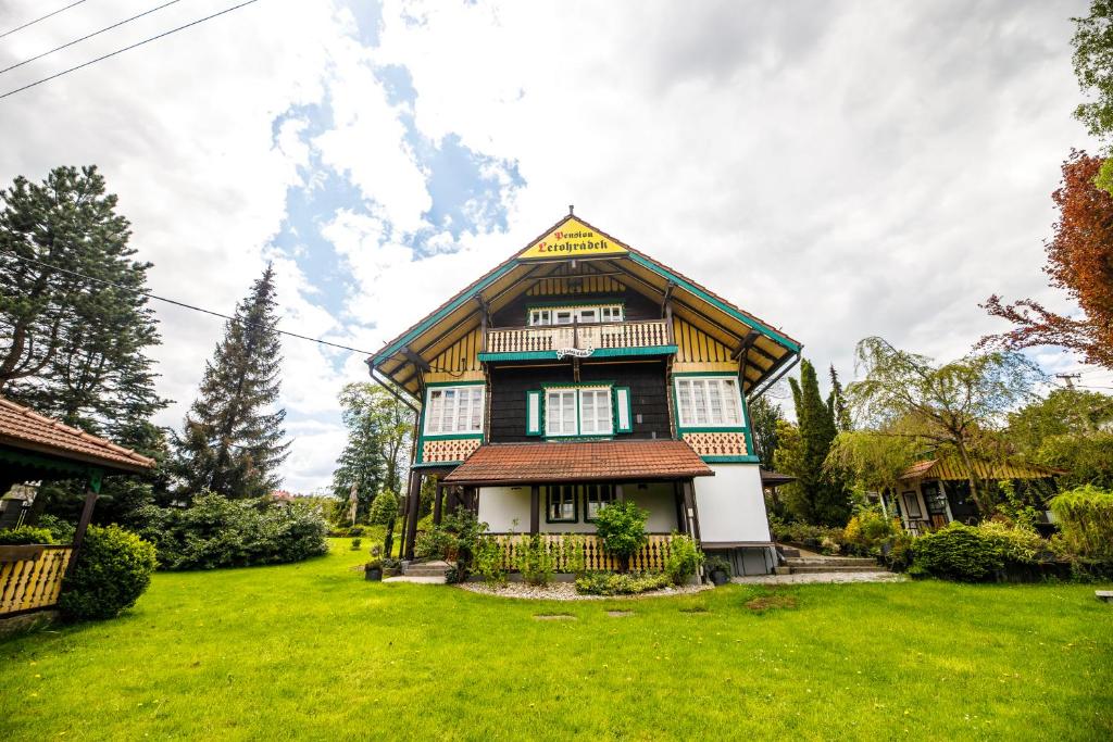 a house with a gambrel roof on a green lawn at Penzion Letohrádek in Frýdlant nad Ostravicí