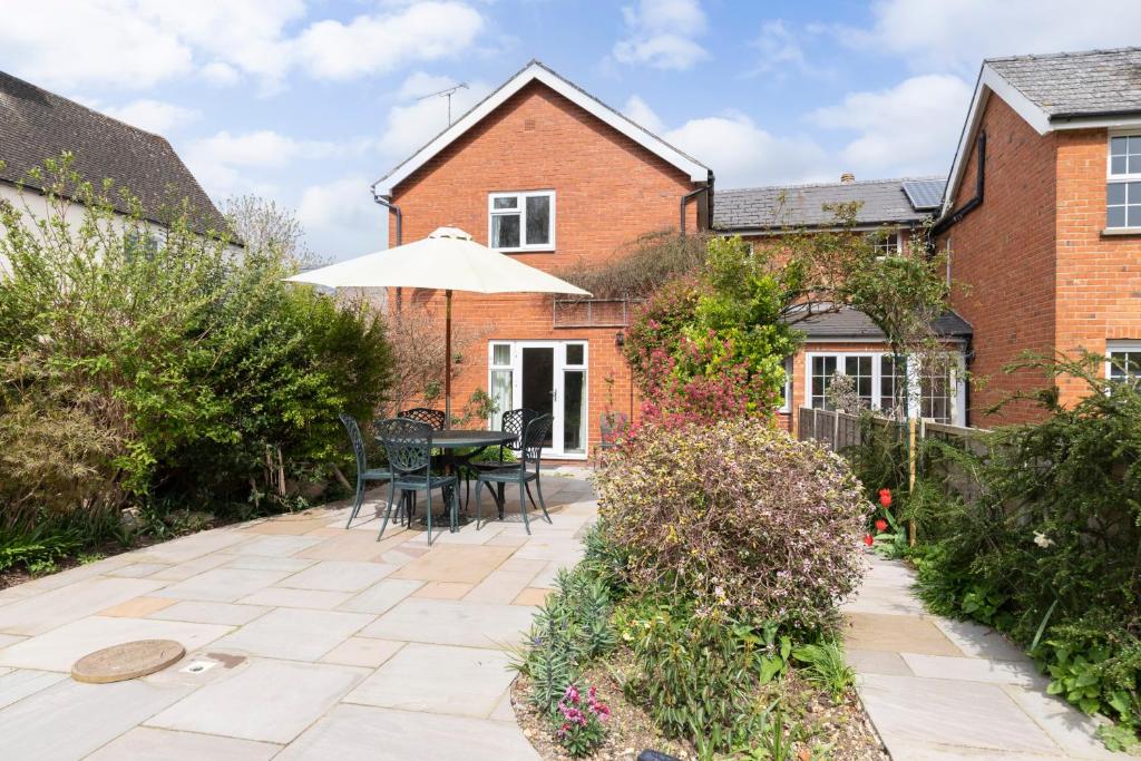 切爾滕納姆的住宿－Luxury Cheltenham Home with EV charger - Lechampton Hills，庭院配有遮阳伞和桌椅。