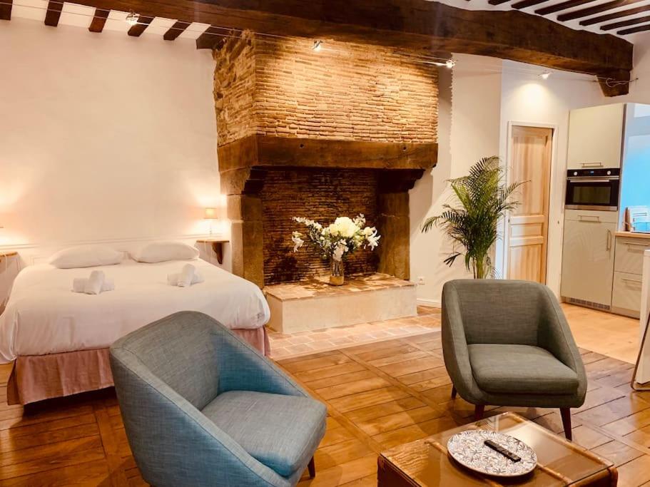 une chambre avec un lit et deux chaises et une cheminée dans l'établissement Le Pandora, Charmant Studio - Hypercentre, à Rennes