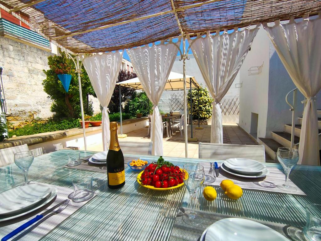 una mesa con una botella de vino y un bol de fruta en La Caura di Casa Camilla Journey en Marina Serra