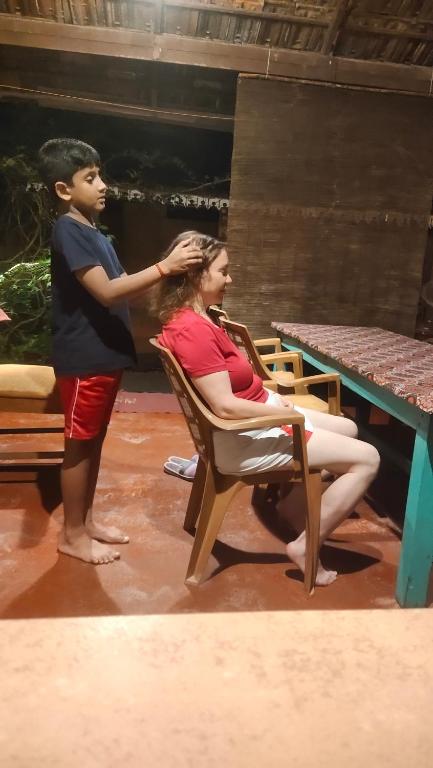 a boy combing the hair of a woman sitting in a chair at Ambadi's villa -Lake view resort in Pallipuram