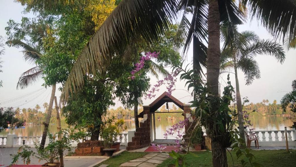 a gazebo in a garden with a palm tree at Ambadi's villa -Lake view resort in Pallipuram