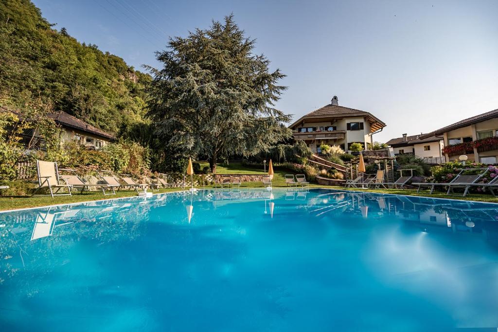 a large pool of blue water in front of a house at Hotel Rierhof in Chiusa