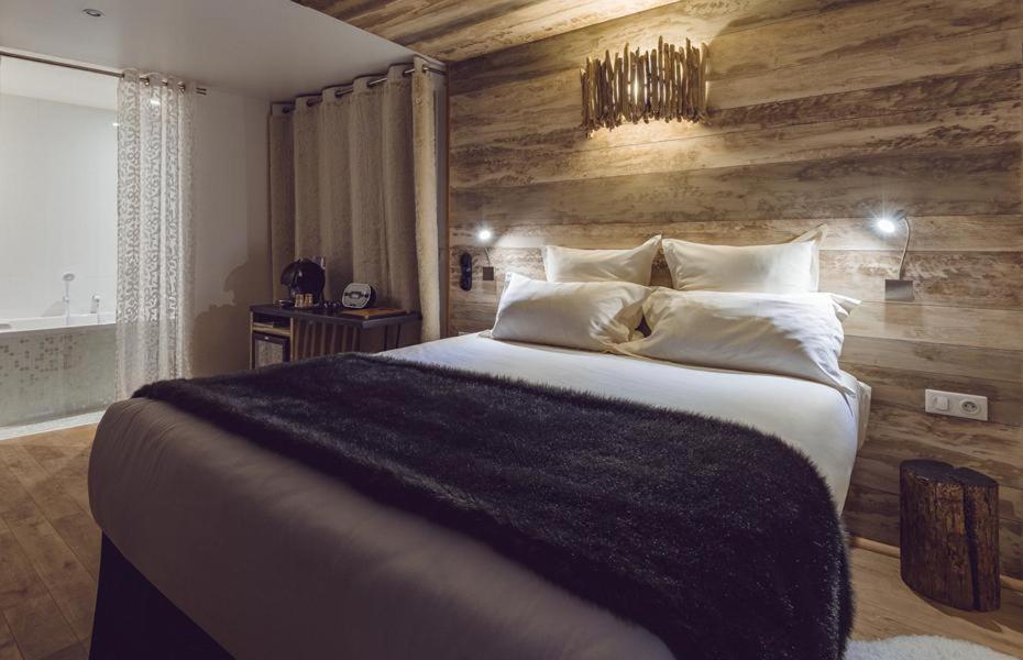 a bedroom with a large bed with a wooden wall at Rock Noir & Spa in La Salle-les-Alpes