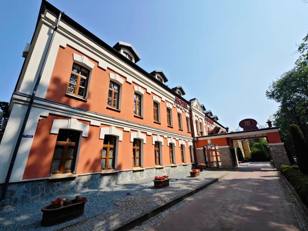 un edificio naranja y blanco con flores en un patio en Hotel Koronny, en Zamość