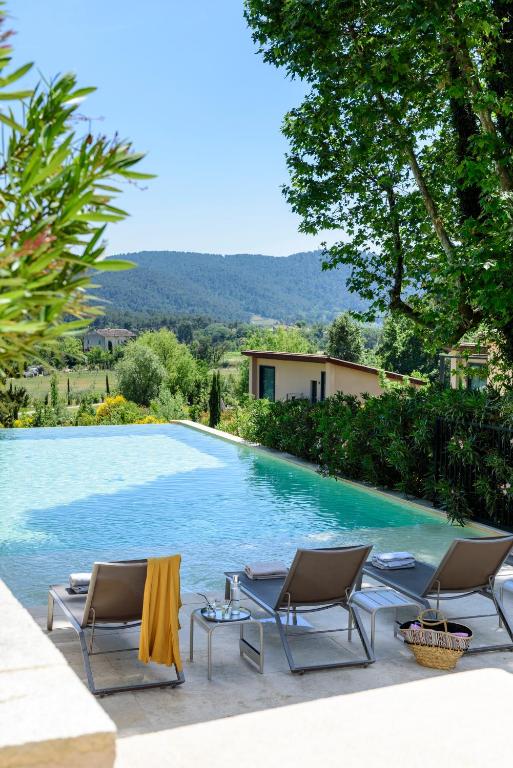 une piscine avec deux chaises et une table à côté dans l'établissement Les Lodges Sainte-Victoire Hotel & Spa, à Aix-en-Provence