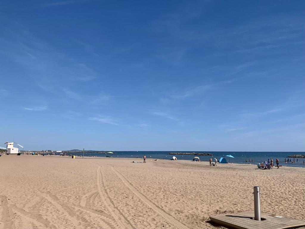 a beach with people and the ocean in the background at A 50m de la plage, appartement pour 6 personnes avec terrasse in Valras-Plage