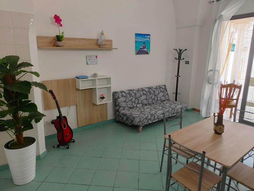 sala de estar con sofá y mesa con guitarra en La Locanda, en Nociglia