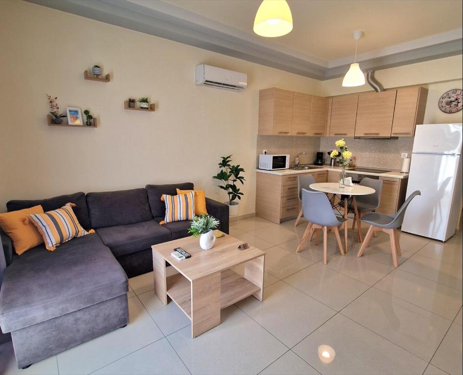 a living room with a couch and a table and a kitchen at comfy center rodos - luxury in Asgourou