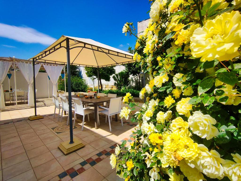 Lu Purpu di Casa Camilla Journey في مارينا سيرا: فناء به طاولة ومظلة وزهور صفراء