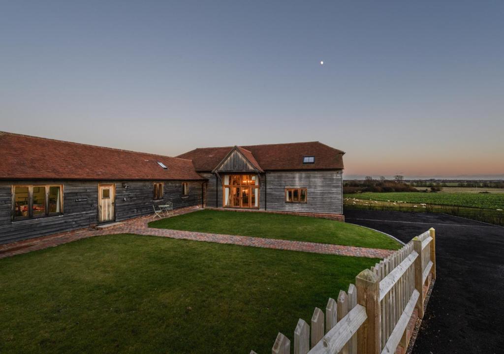 a house with a fence in front of a yard at The Old Cowshed in Stone