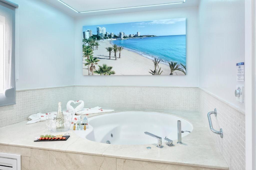 baño con bañera y pintura de playa en Hospedium Hotel Abril en San Juan de Alicante