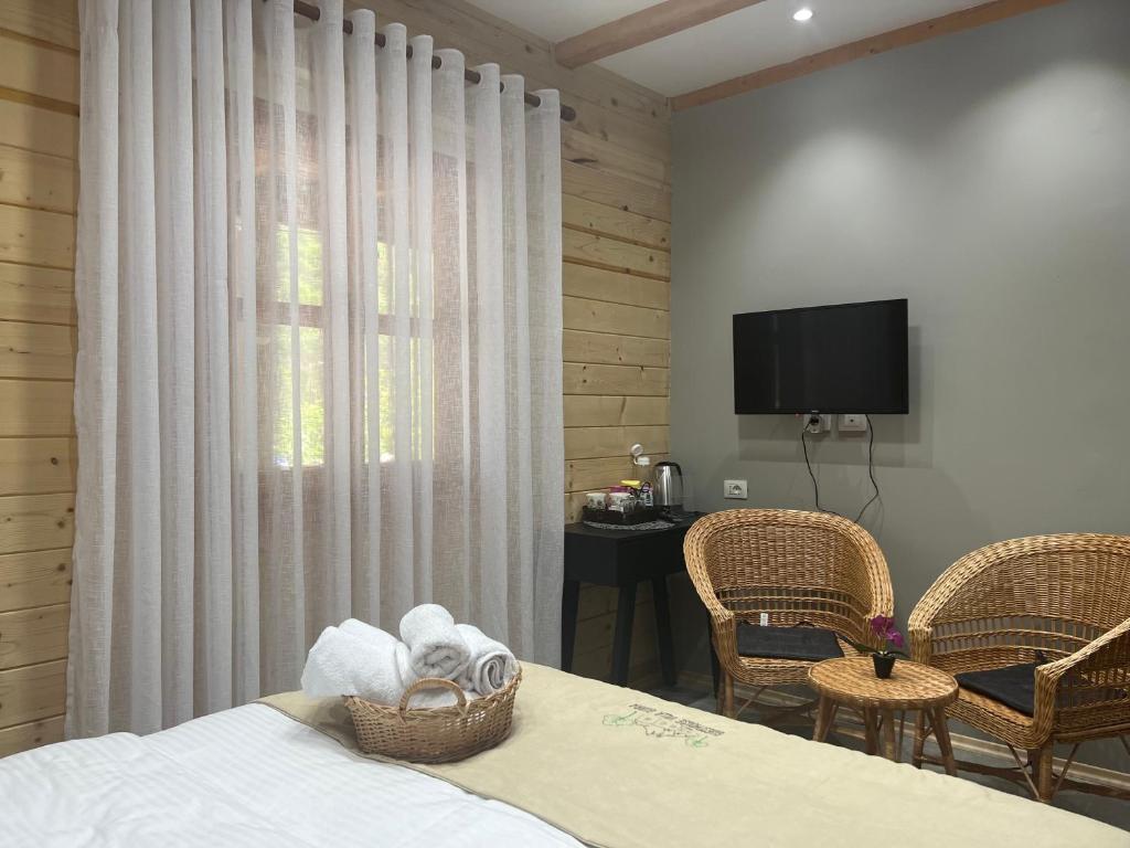 a bedroom with a bed with a television and chairs at Guesthouse Villa Gurra in Theth