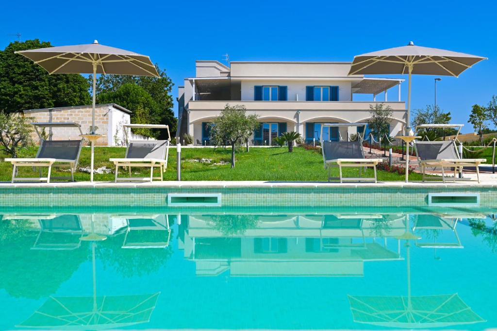 una piscina con sillas y sombrillas frente a una casa en Terra Home Resort, en Spongano