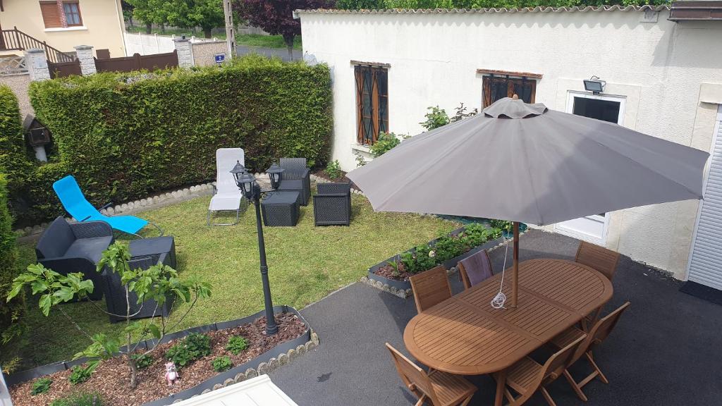 un patio con tavolo, ombrellone e sedie di Maison, jardin, barbecue et vélo classé 3 étoiles a Dives-sur-Mer