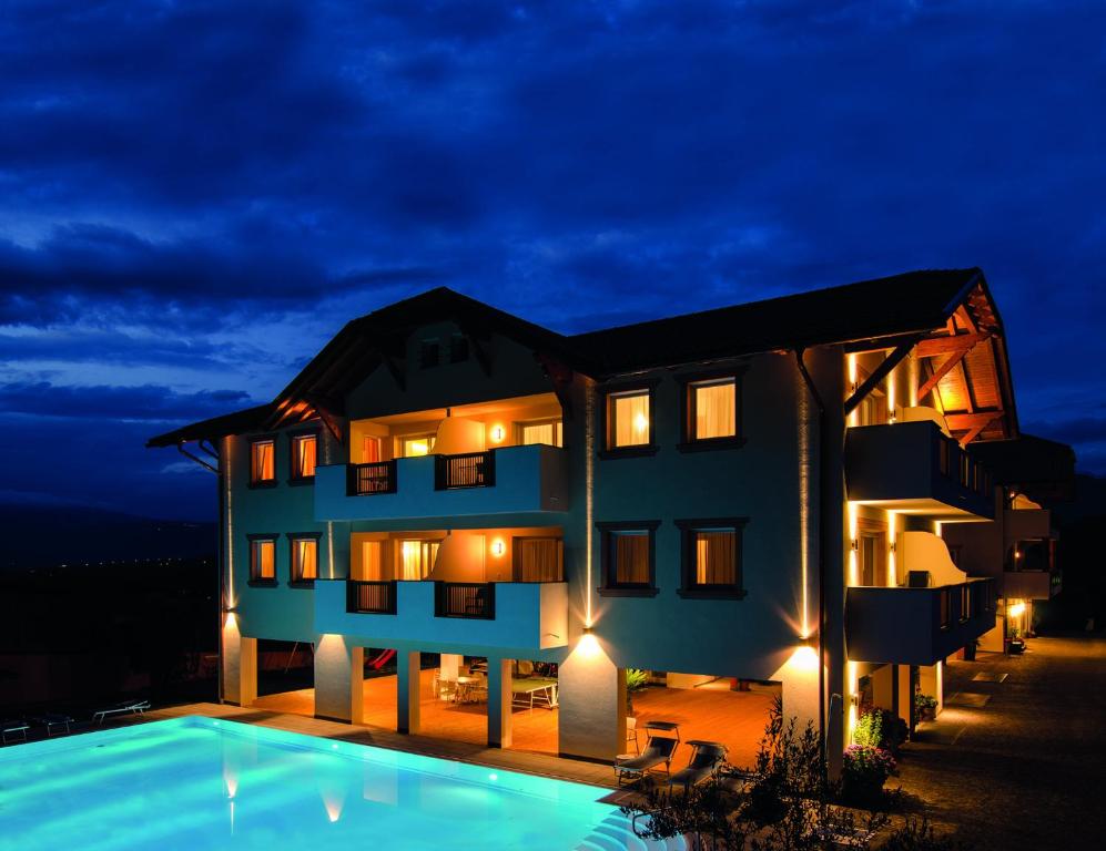 eine Villa mit einem Pool in der Nacht in der Unterkunft Garni Hotel Peterlinhof in Kaltern