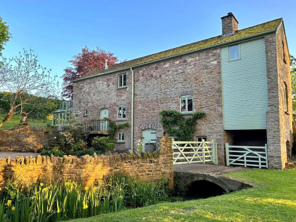 uma antiga casa de pedra com um portão e uma cerca em Beautiful Old Water Mill in Rural Herefordshire em Hereford