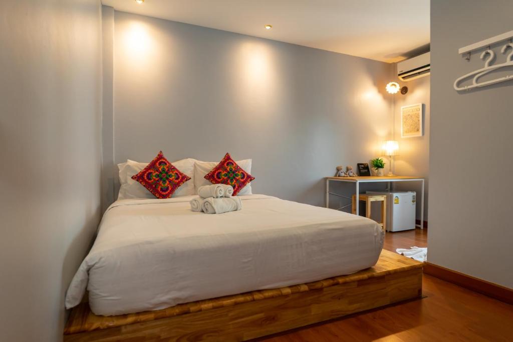 um quarto com uma grande cama branca com almofadas vermelhas em Chiang mai Walking Street Home ( เชียงใหม่วอล์คกิ้งสตรีทโฮม ) em Chiang Mai