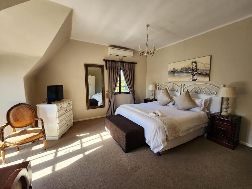 a bedroom with a large bed and a chair at Dark Chocolate Guest House in Durbanville