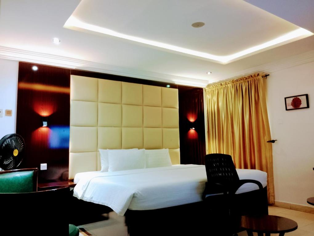 - une chambre avec un grand lit blanc et une chaise dans l'établissement Brickland Residence, à Abuja