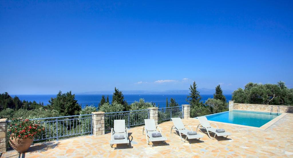 a villa with a swimming pool and lounge chairs at Monodendri Blue in Georgoutsátika
