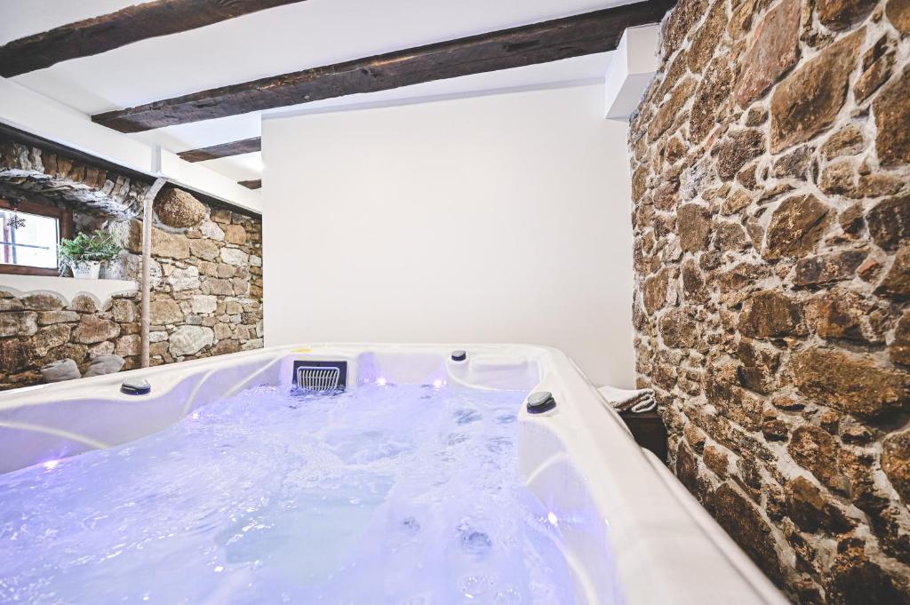 a bath tub in a room with a stone wall at HEDONIA in Fužine