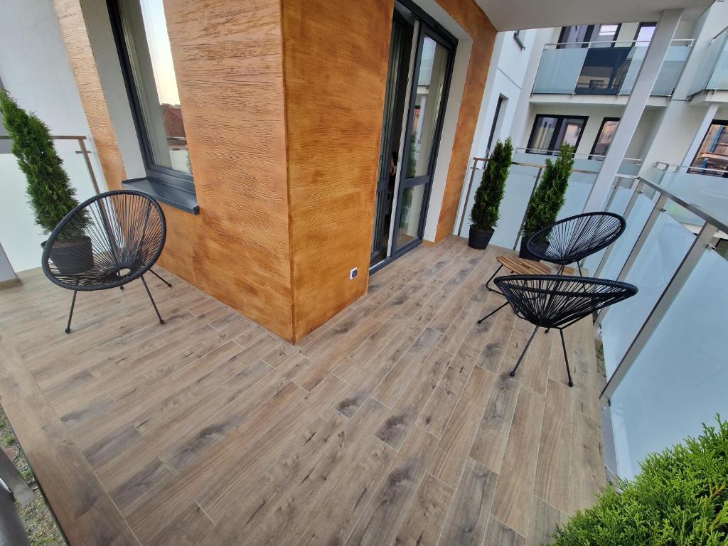duas cadeiras sentadas num piso de madeira em frente a um edifício em Apartament 6 em Goldap