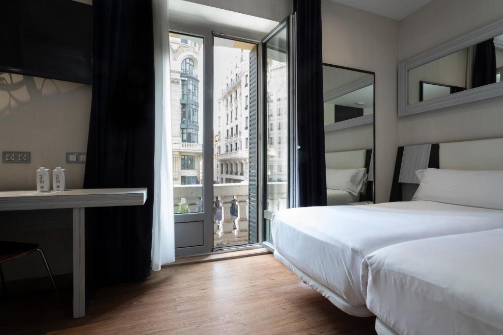 Un dormitorio con una cama y una ventana grande. en Petit Palace Triball, en Madrid