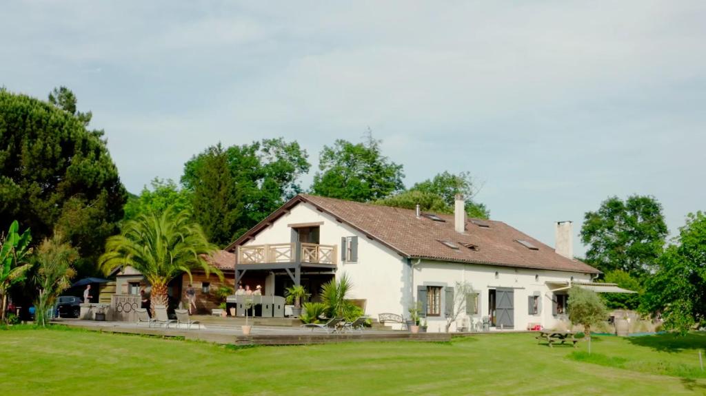 una grande casa bianca con un cortile verde di La Belle Landaise 1809 Gîte Arridoulet 1 a Peyrehorade