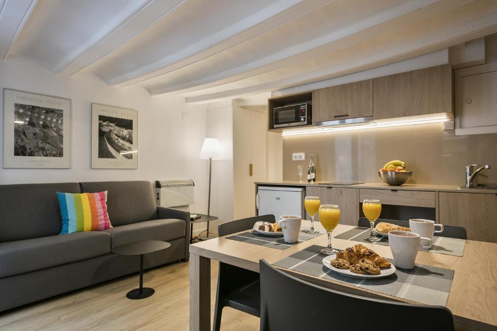 een keuken en een woonkamer met een tafel en een bank bij Ola Living Vidreria in Barcelona