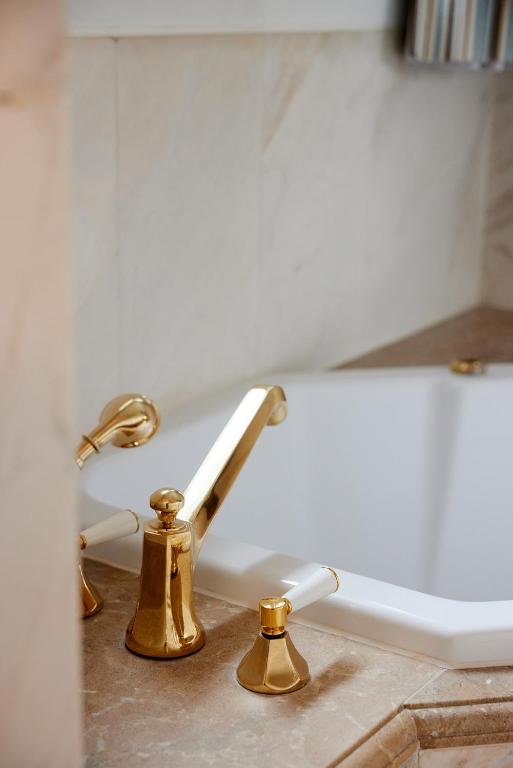 a bathroom sink with gold faucets and a bath tub at Château Gütsch in Luzern