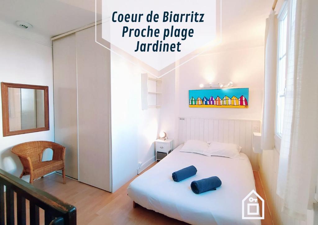a bedroom with a white bed with blue pillows on it at Lalanne Btz, Duplex Jardinet près de la Plage in Biarritz