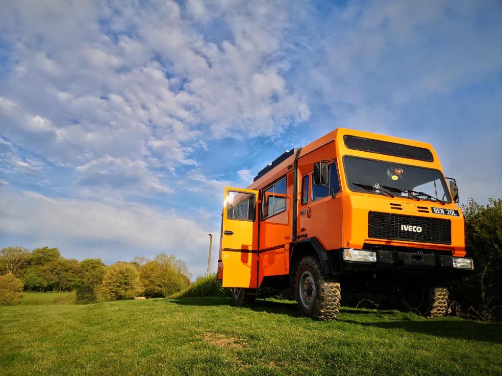 un camion orange garé dans une prairie dans l'établissement Glamp in Style in a Converted Army Truck, à Battle