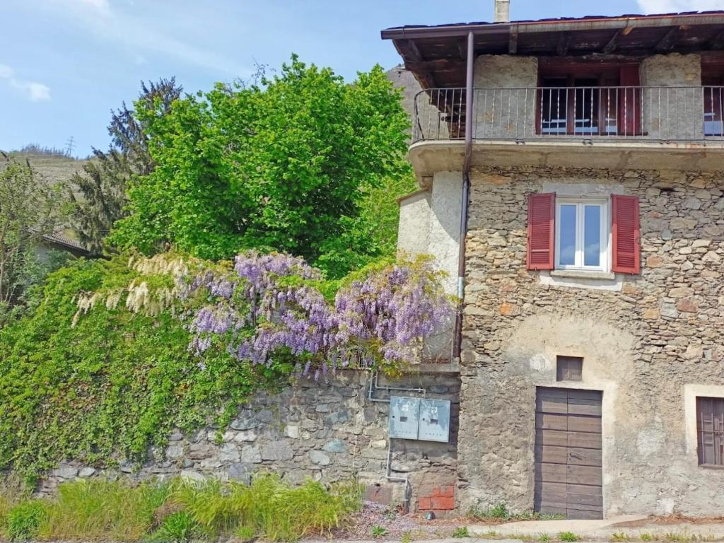 an old stone building with a window and purple flowers at Al Termen in Sondrio