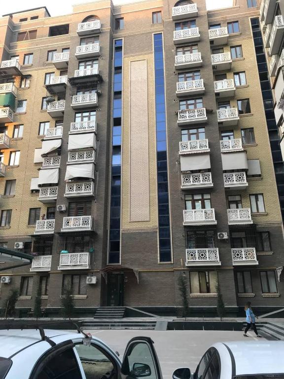 um edifício alto com uma pessoa a andar na frente dele em GREEN HAUS ONE em Tashkent