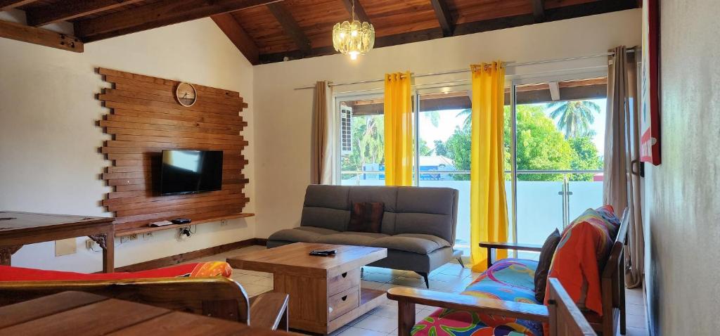 a living room with a couch and a tv at Appartements au cœur de Maharepa in Maharepa