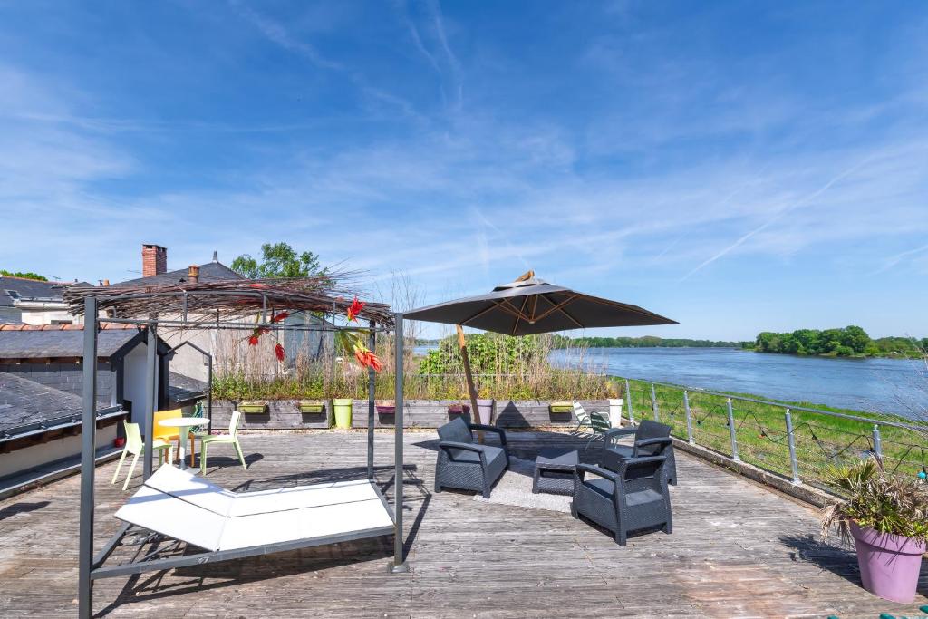 un patio avec une table, des chaises et un parasol dans l'établissement Superbe Appartement Vue sur la Confluence LOIRE, à Bouchemaine