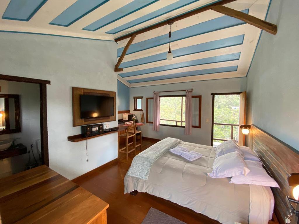 a bedroom with a large bed with a blue ceiling at Serra dos encantos in Lavras Novas