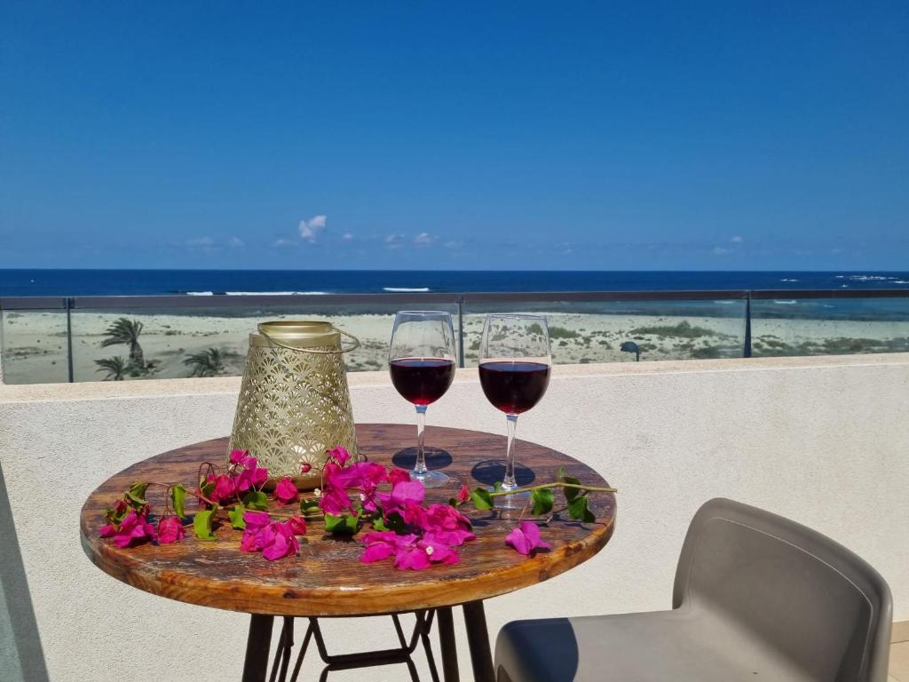 una mesa con dos copas de vino y flores en Ola Cotillo! Ver y Sentir el Mar desde casa, en Cotillo