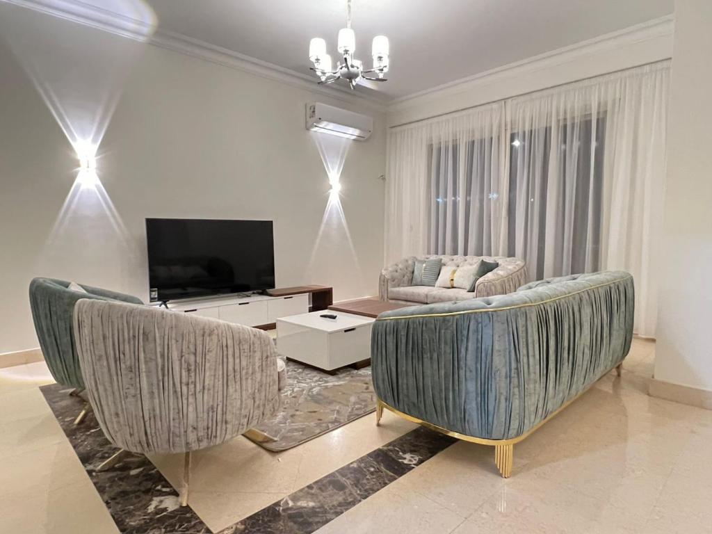 a living room with two chairs and a television at Elite Residence in Sheikh Zayed