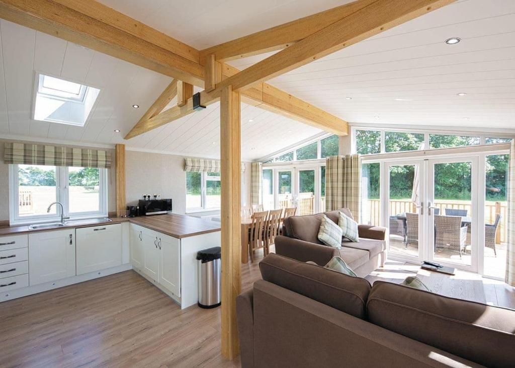 a living room with a couch and a kitchen at Athelington Hall Farm Lodges in Horham