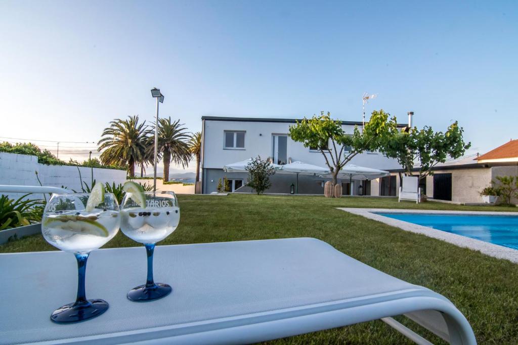 dos copas de vino sentadas en una mesa cerca de una piscina en Villa las sinas 2 - As Sinas - Pontevedra, en Villanueva de Arosa