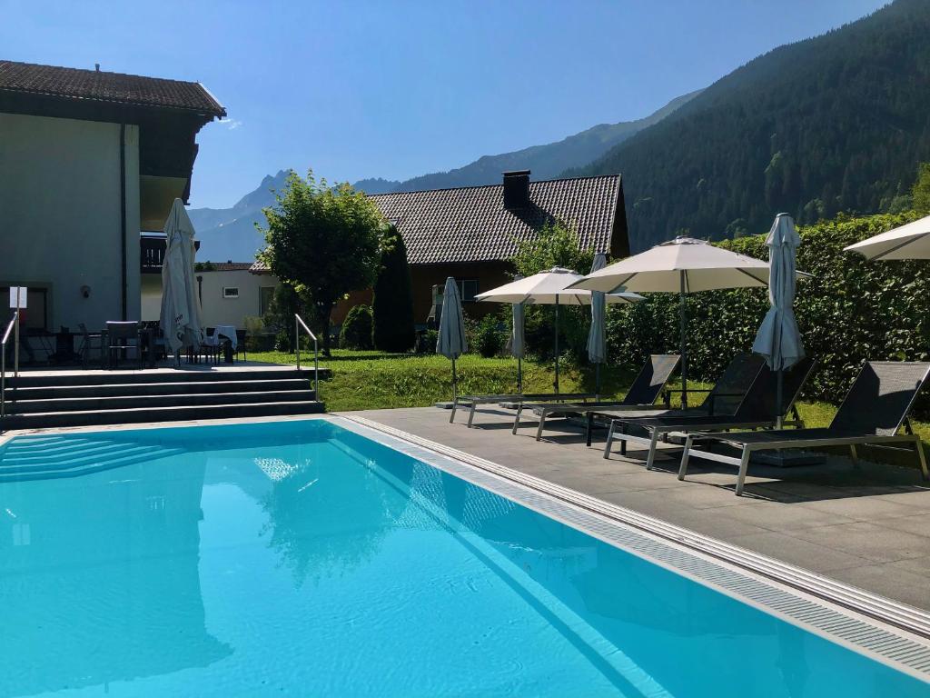 a swimming pool with chairs and umbrellas next to a house at Appart Laijola in Gaschurn