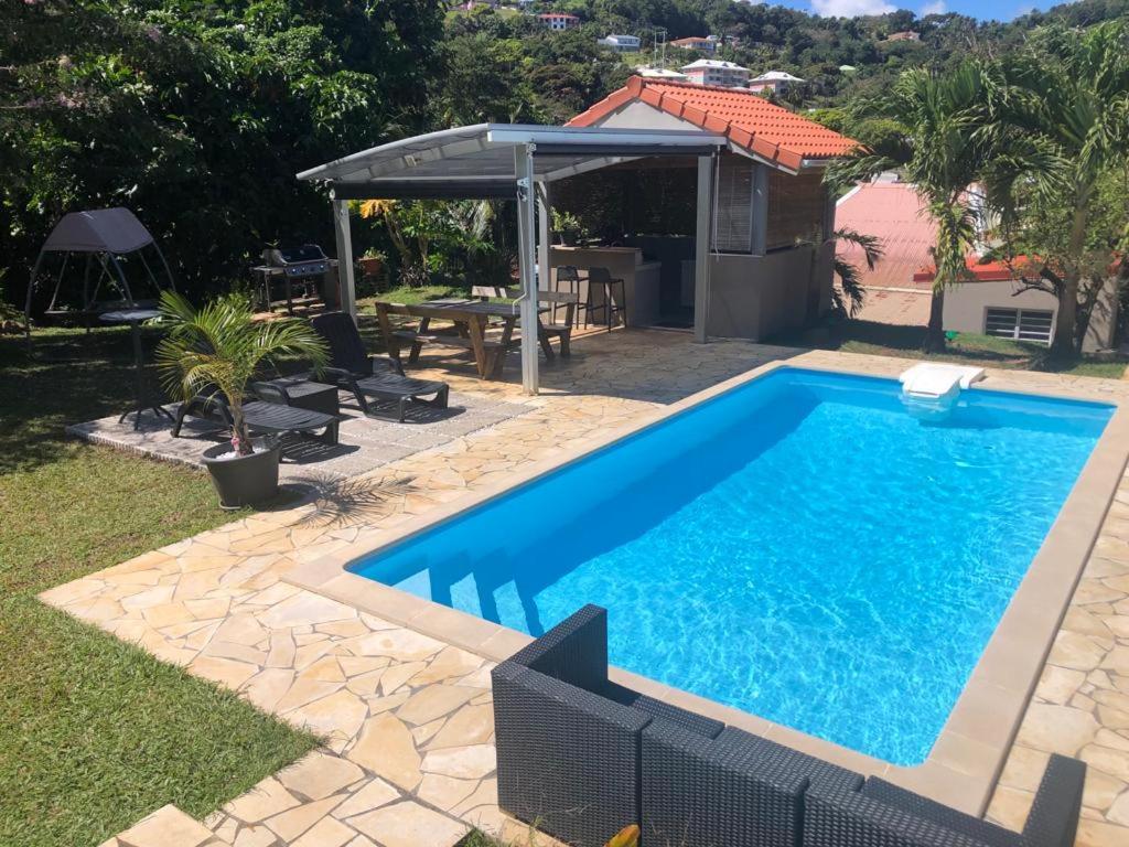 a swimming pool in a yard with a table and a pavilion at L' authentique in La Trinité